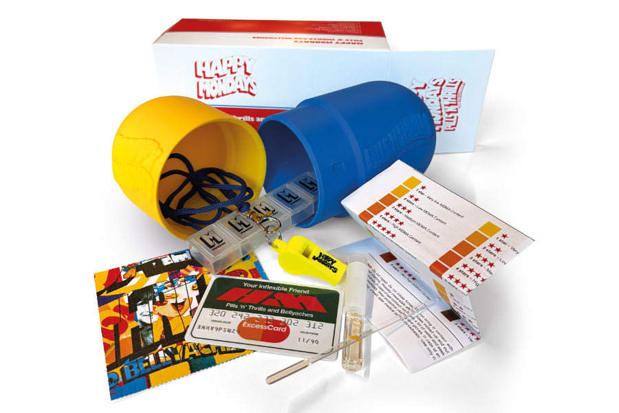 Colorful gag gift kit with a yellow and blue capsule-shaped containers, toy pills, and cards from the 'Pills ’n Thrills and Bellyaches' set.